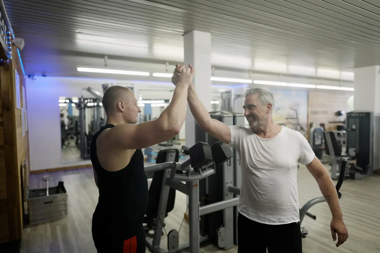 Zwei Mitglieder geben sich ein High-Five an der Kabelzugstation