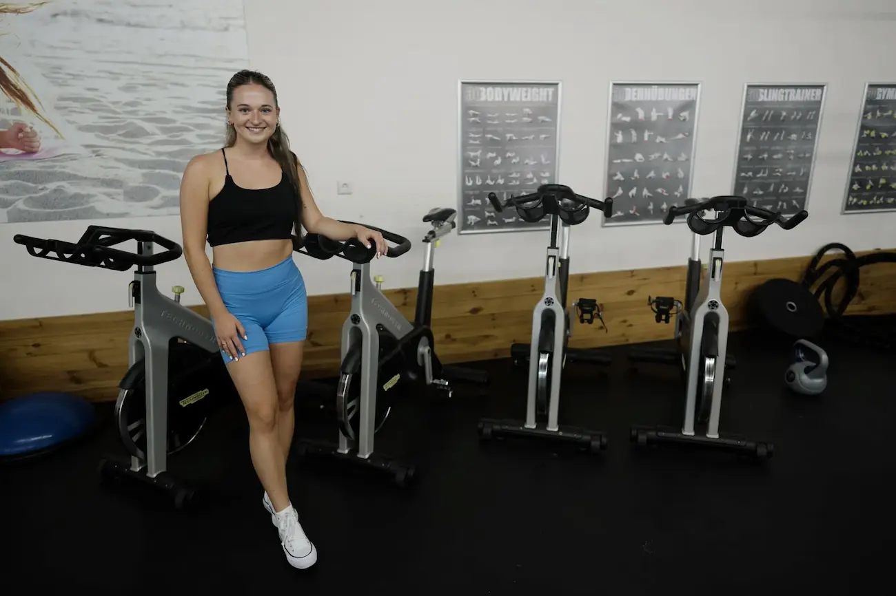 Mitglied im Indoor-Cycling-Bereich vor den Übungsplakaten