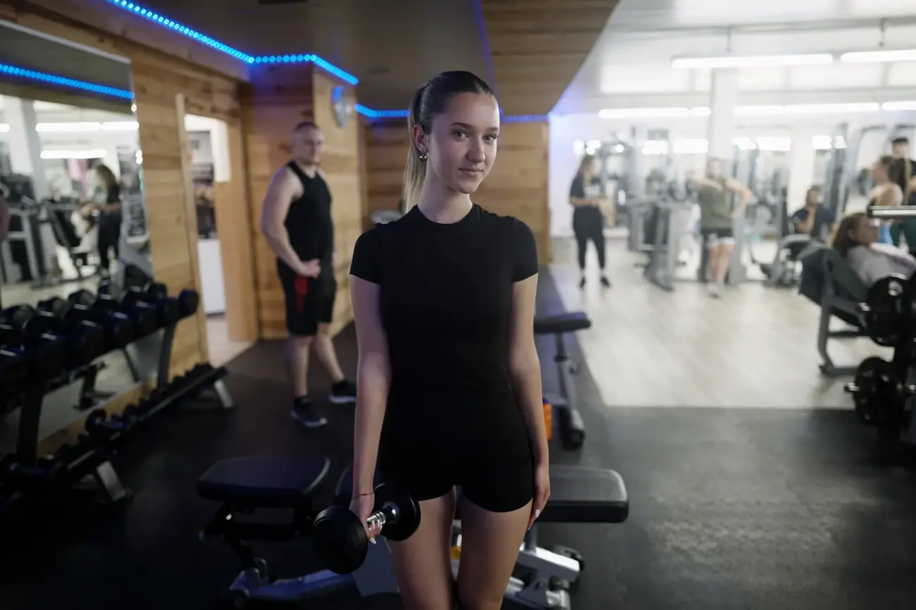 Mitglied posiert mit Kurzhantel im Trainingsbereich